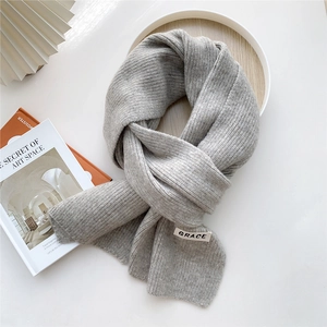 Detailed view of grey knit scarf with GRACE label texture on aesthetic background