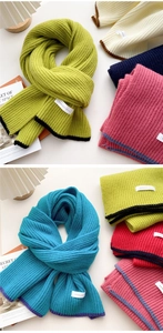 Detailed texture of thick knit scarves with contrasting borders and woven brand labels