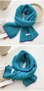 Close-up of knit scarf texture with teal blue fabric, purple trim and brand tag detail