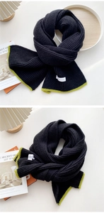 Close-up of black knit scarf with neon green contrast edges in a cozy home setting