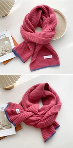 Detail of peach pink knitted scarf with navy blue borders and woven brand label