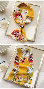 Detailed view of yellow floral silk scarf with large red blossoms and 100% polyester tag