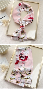 Detail view of pink silk scarf with red floral patterns used as an elegant neck tie
