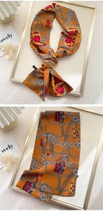 Detail of a silk-like narrow scarf with vintage crown and golden chain patterns