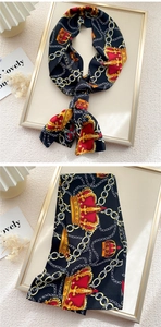 Detail of a vintage black satin skinny scarf with golden chain and royal crown patterns