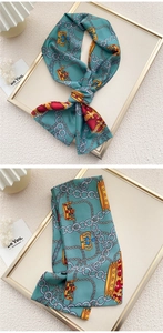 Detail of teal satin scarf featuring golden crown patterns and elegant chain prints