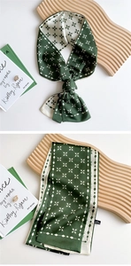 Detailed view of dark green silk scarf with geometric patterns tied in a bow