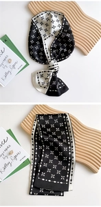 Macro detail of silk-like neck scarf with black and white star pattern and geometric border