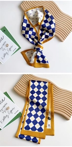 Detail of silk scarf showing checkerboard pattern and luxury texture on wooden tray