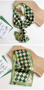 Detail of green and yellow checkerboard silk scarf with R-letter print on decorative edges