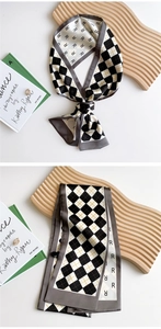 Detail of checkered narrow silk scarf with letter R pattern on wooden tray