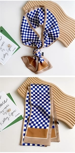 Detail showing checkered patterns and knots on a long silk scarf for women in blue