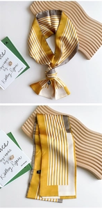 Detail of yellow striped narrow silk scarf with elegant knot and satin texture