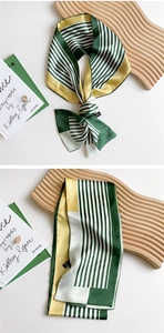 Close-up of narrow silk-feel scarf with geometric stripes in green and yellow