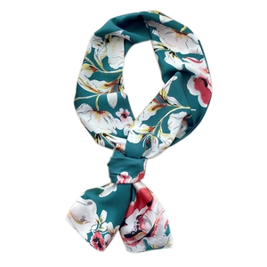 Elegant dark green floral silk scarf with large blooms tied in a bow on white background