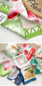 Detail showing various silk scarf patterns with fruit and floral prints and satin texture