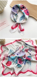 Detail view of floral print silk scarf featuring pink wavy edges and vibrant flower clusters