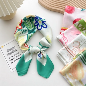 Silk-like square scarf with floral prints tied as a bow on a wooden tray decor