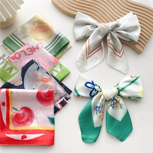 Silk-like square scarves with assorted floral prints displayed on a minimalist surface