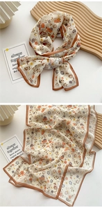 Detail of long floral silk scarf with brown edges and orange blossom patterns