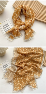Close-up of ginger yellow silk scarf with small white floral print and gray piping