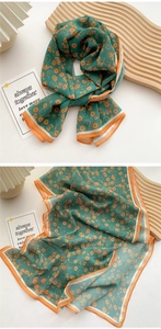 Detail of silk-feel long scarf in dark green with orange floral print and striped edges