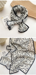 Detail of lightweight long scarf featuring black floral print and fine hemmed edges