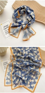 Detail of floral long silk scarf in blue with orange borders on a decorative background