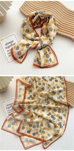 Detail view of lightweight floral silk scarf with orange hem and soft petal patterns