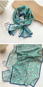 Detail of mint green long silk scarf with leaf prints and blue contrast borders