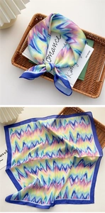 Detail eines quadratischen Seidentuchs mit buntem Batikwellenmuster und blauem Rand