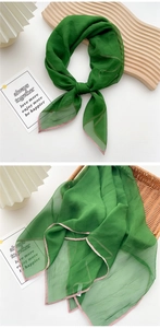 Detail of emerald green thin square silk scarf with pink stitched edges and crinkled texture