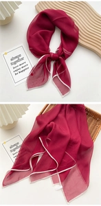 Detail of dark red lightweight silk scarf with white contrast edges and soft texture