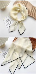 Close-up of light beige silk scarf with black piping edges on a woven basket