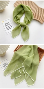 Detail of grass green silk scarf showing lightweight translucent texture and white rolled edge