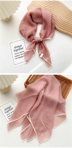 Macro view of light pink silk scarf with delicate white rolled edges in a wicker basket