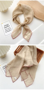 Detail of thin apricot silk scarf featuring delicate pink hand-rolled edges and fabric texture