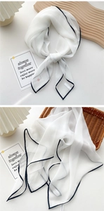Detail of white silk scarf with black contrast hem edges and light breathable texture