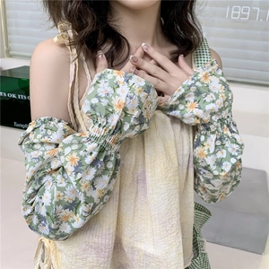 Close-up of green floral sun protection sleeves with white daisy patterns and ruffles
