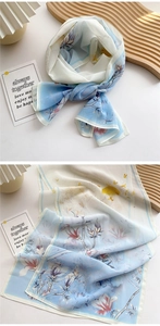 Detail of light blue floral chiffon scarf featuring ink-style flower and bird patterns