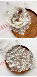 Detail of cream lace triangle scarf with floral embroidery and scalloped edges