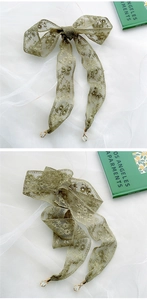 Detail eines olivgrünen Spitzenschals mit Blumenstickerei und Goldmetallanhänger