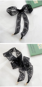 Detail eines schwarzen Spitzenbands mit elegantem goldenem Karabinerverschluss und Schleife