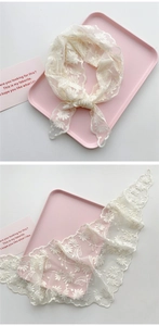 Detail eines weißen Spitzen-Stirnbands mit feiner Gänseblümchen-Stickerei und Netzstruktur
