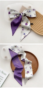 Detail of narrow silk scarf featuring purple floral patterns and cursive script lettering