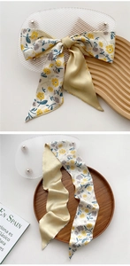 Detail showing elegant floral silk scarf with script pattern used as a hair accessory