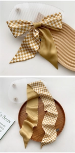 Macro shot of narrow satin scarf with yellow checkerboard pattern and smooth texture