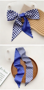 Close-up of blue and white checkerboard silk scarf tied in a bow on a wooden display