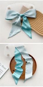 Close-up of a double-sided light blue silk scarf tied in a bow on a wooden tray
