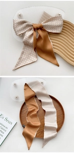 Detail of a thin silk scarf showing houndstooth pattern and solid coffee brown side